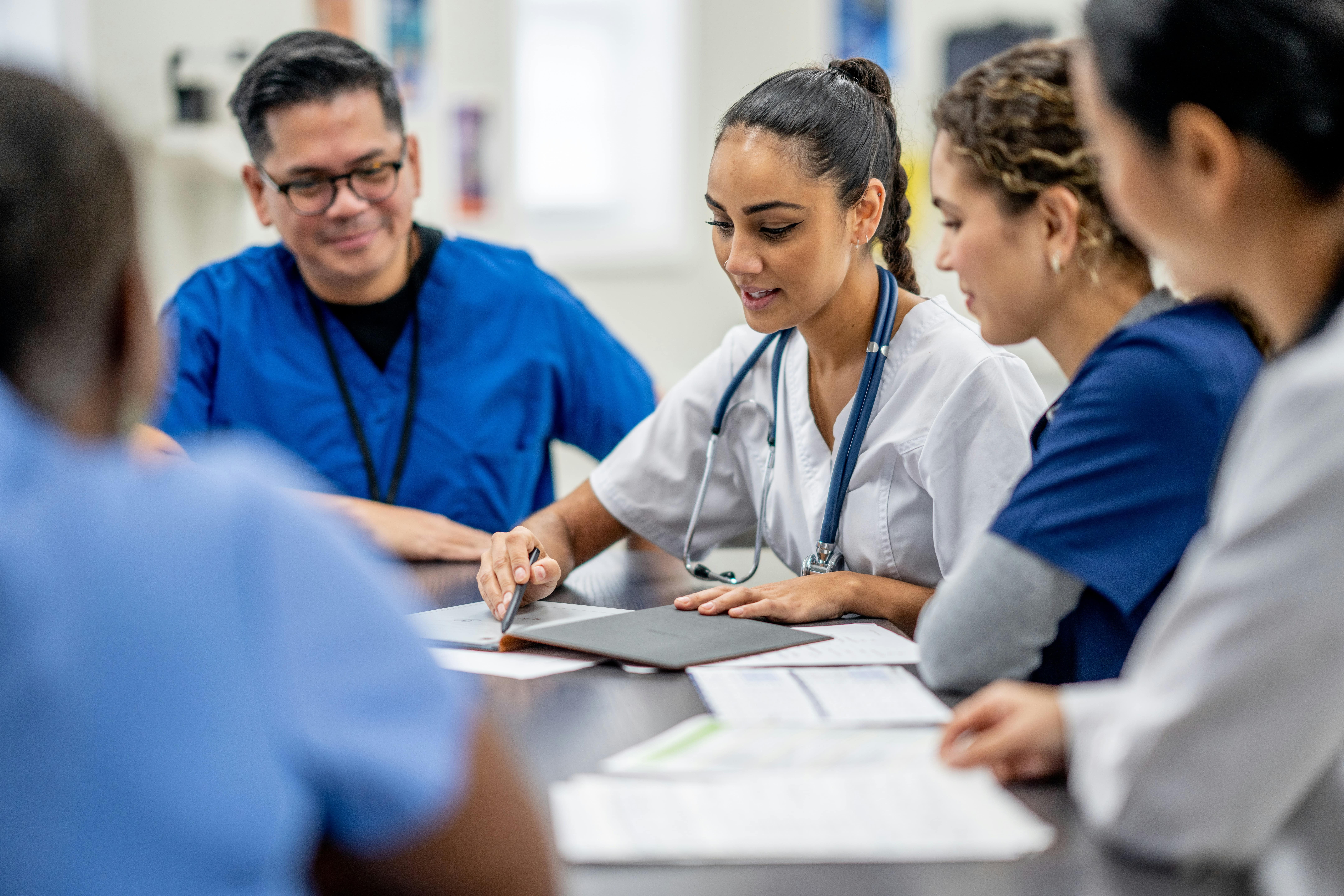 Healthcare professionals sit together at a table reviewing documents.